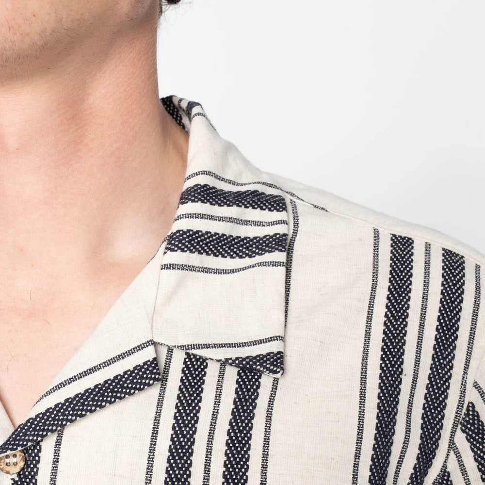 Close-up of a person wearing a white shirt with black striped patterns on a plain background