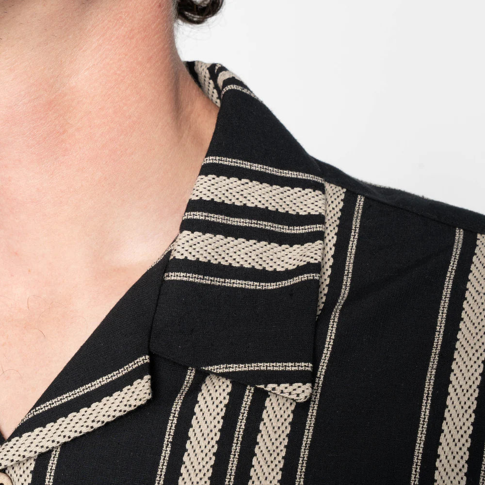 Close-up of a black garment with beige striped patterns on a white background