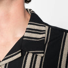 Close-up of a black garment with beige striped patterns on a white background