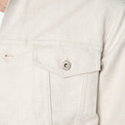 Close-up of a light-colored denim jacket with a button on a white background