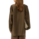 Woman wearing a brown outfit holding a patterned bag on a white background