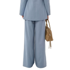 Person wearing a light blue suit with a brown handbag on a white background
