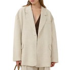 Woman wearing a beige blazer and pants with a plain background