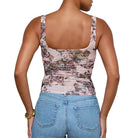Woman wearing a floral tank top and blue jeans on a plain background