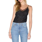 Woman wearing a black top and light blue jeans on a white background