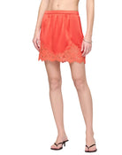 Person wearing a coral lace-trimmed skirt on a white background