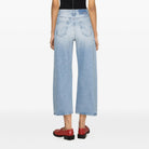 Person wearing a black tank top and light blue jeans on a white background