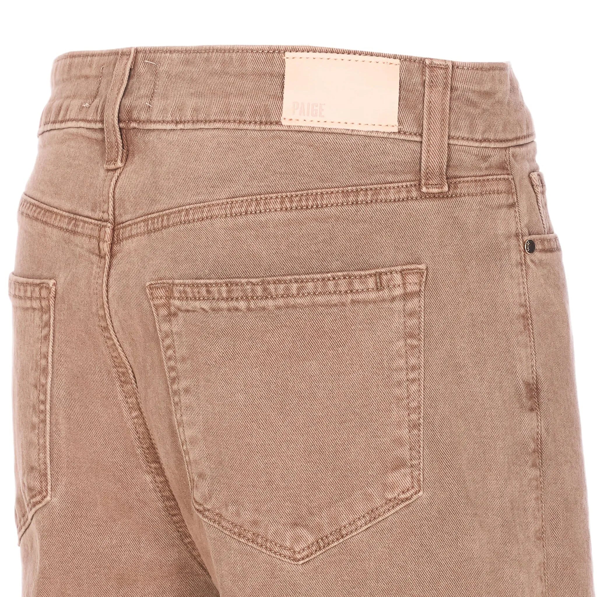 Close-up of brown pants with a visible brand label on a white background