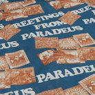 Patterned fabric with 'Greetings from Paradeus' text and vintage-style designs on a blue background.