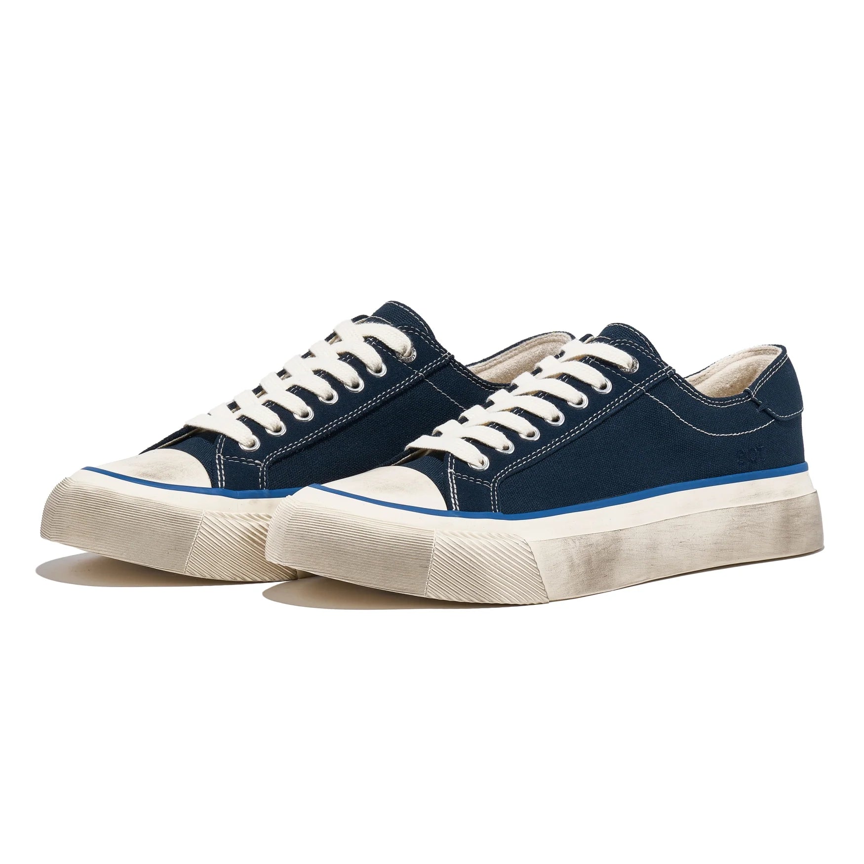 Pair of navy blue sneakers with white laces and soles on a white background