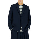 Man wearing a navy suit with a striped shirt on a white background