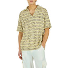 Man wearing a patterned shirt and white pants on a white background