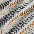 Close-up of a fabric with a pattern of orange and navy stripes on a white background