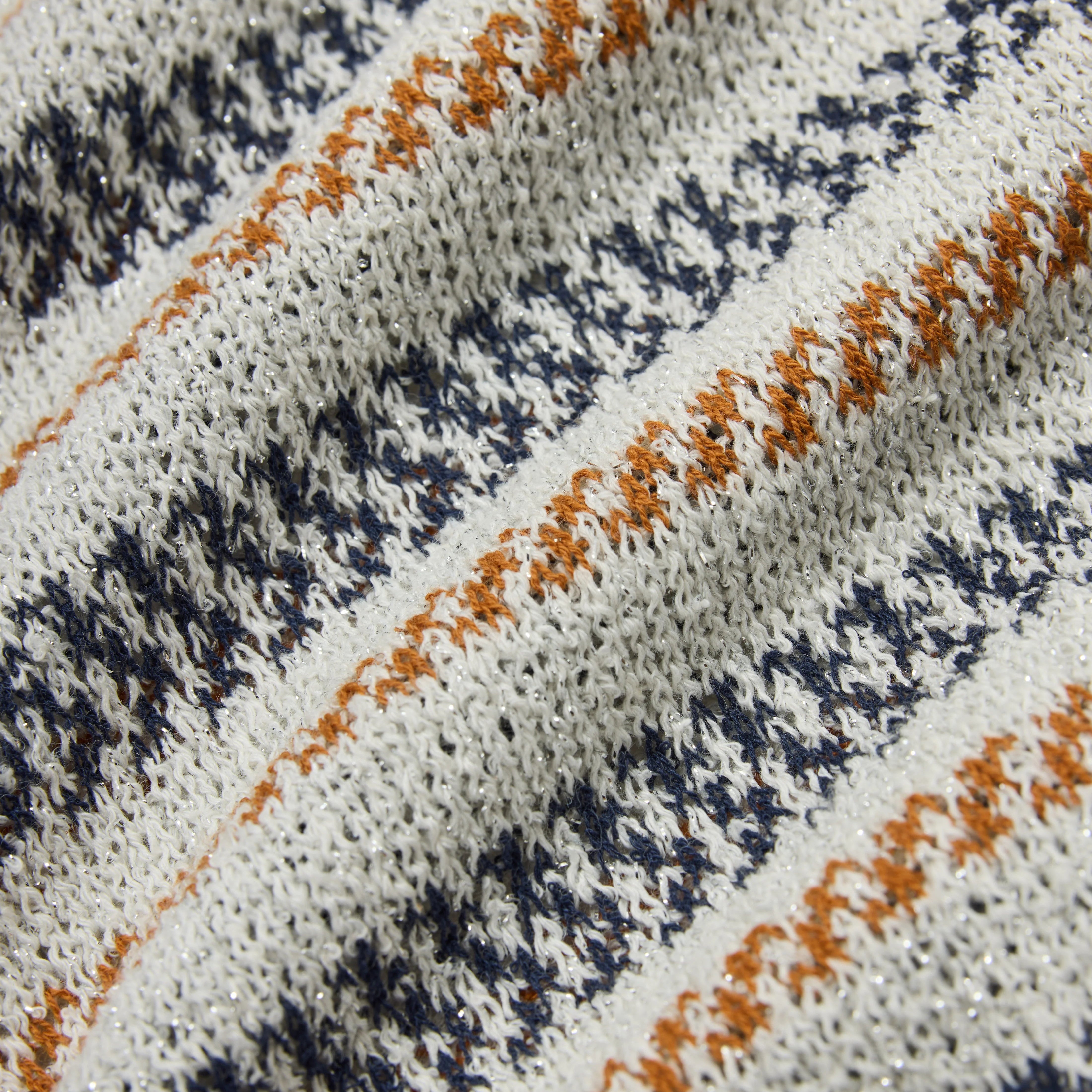 Close-up of a fabric with a pattern of orange and navy stripes on a white background