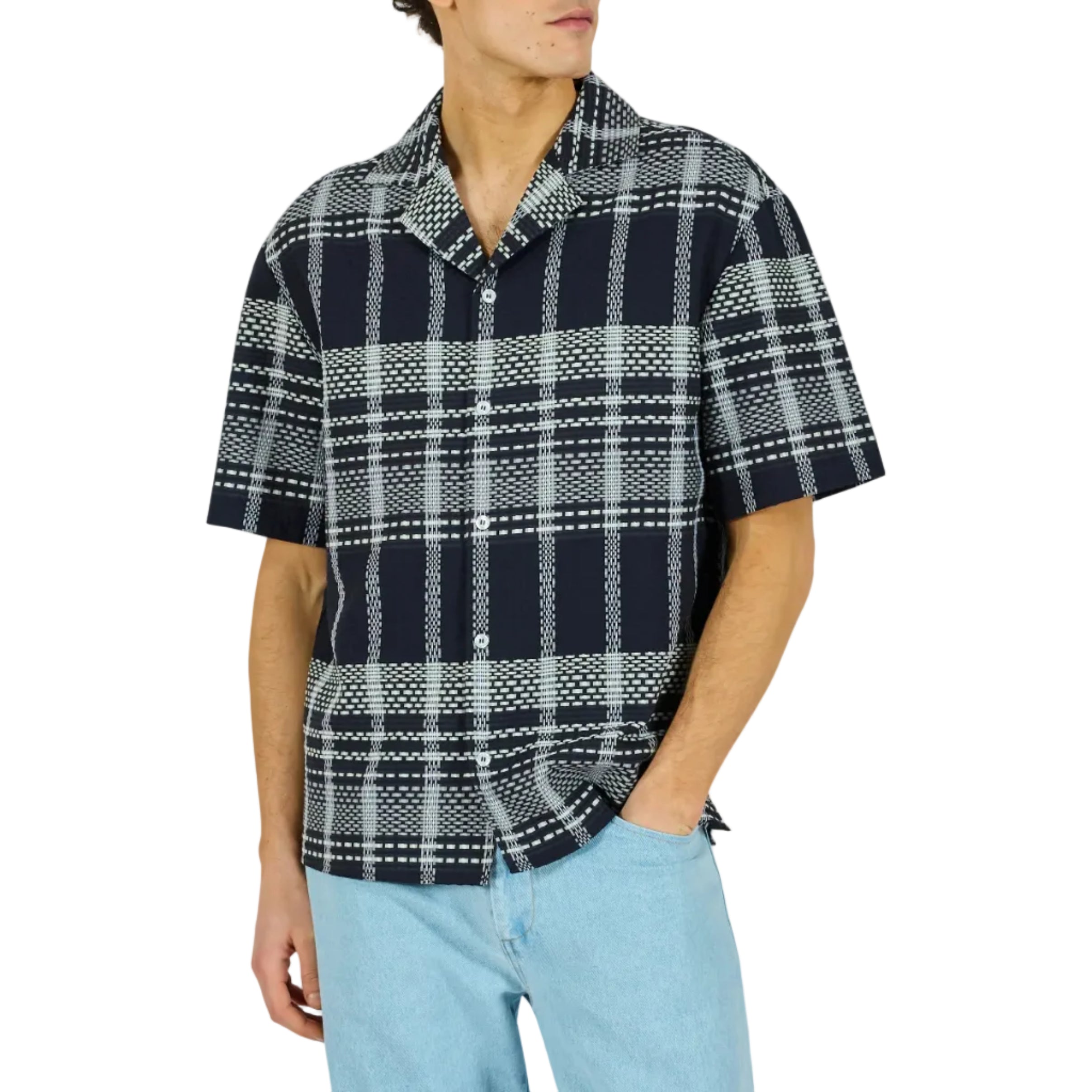 Man wearing a plaid shirt and light blue pants on a white background