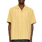 Man wearing a yellow textured shirt with patterned pants on a white background