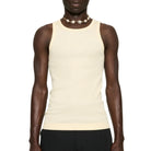 Man wearing a beige tank top and black pants on a white background