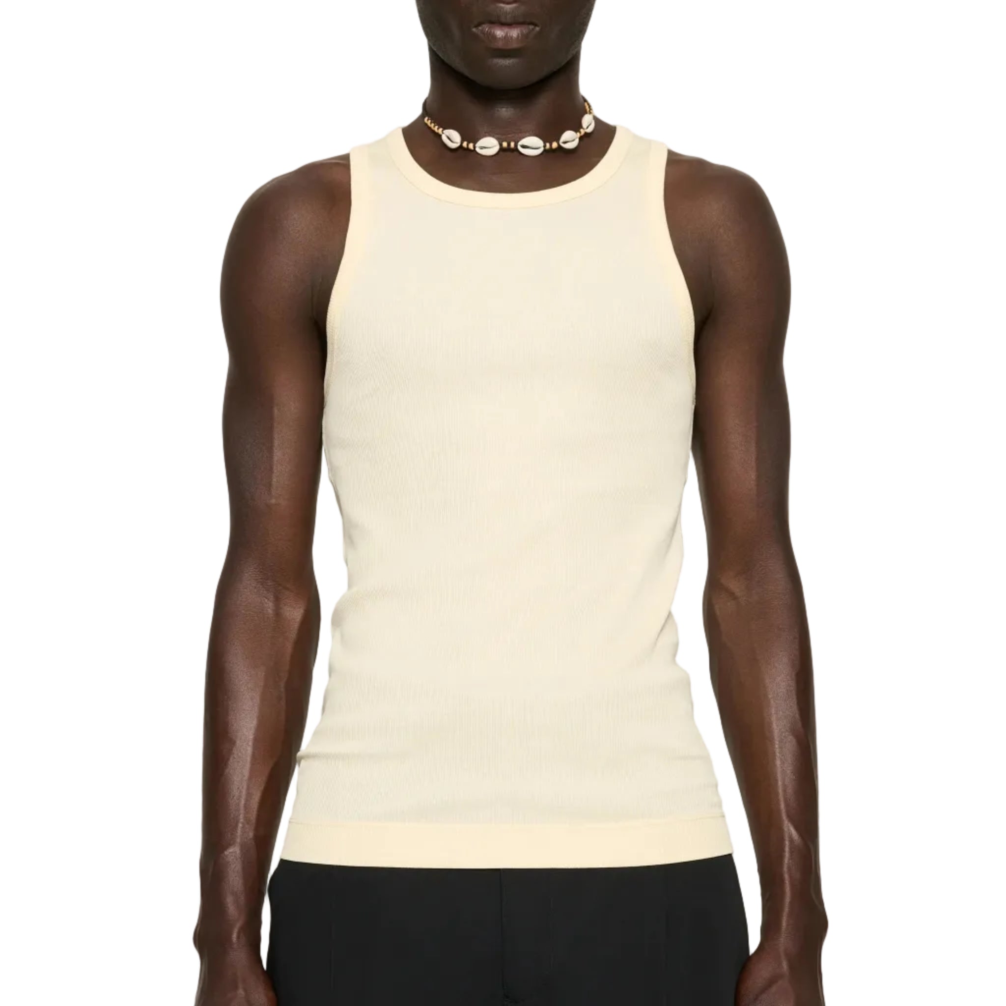 Man wearing a beige tank top and black pants on a white background