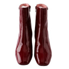 Pair of red patent leather ankle boots on a white background