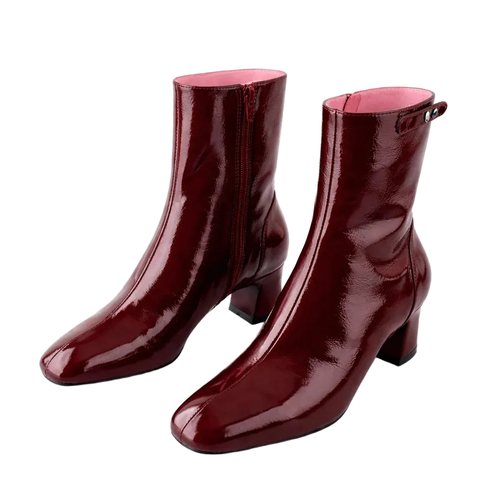 Pair of glossy burgundy ankle boots on a white background