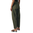 Person wearing a dark green top and green pants against a neutral background