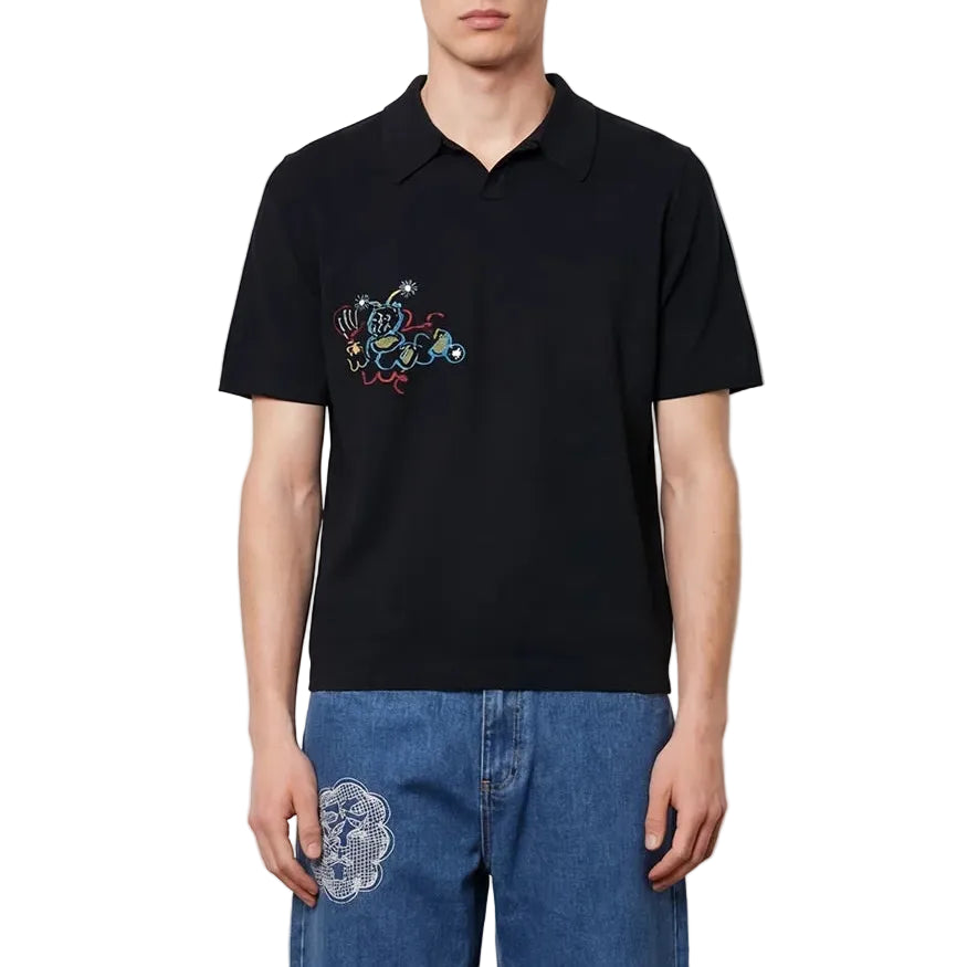 Man wearing a black polo shirt and blue jeans against a white background