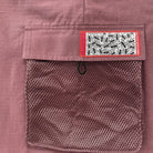 Close-up of a pocket on a pinkish-brown fabric with a patterned label.