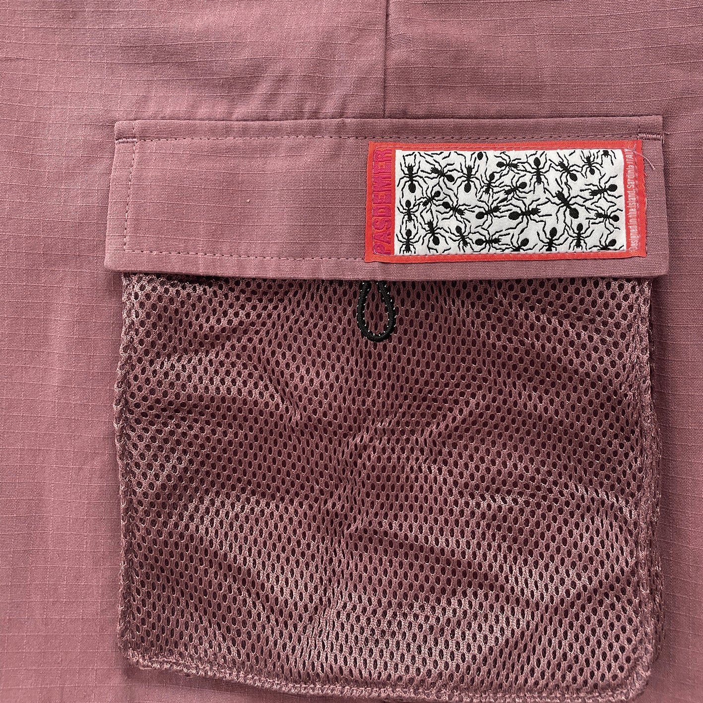 Close-up of a pocket on a pinkish-brown fabric with a patterned label.
