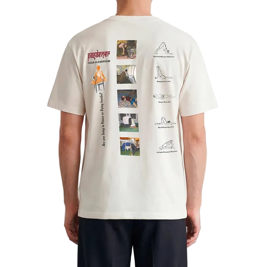 Person wearing a white t-shirt with a graphic design on the back, standing against a plain white wall.