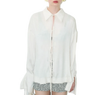 Woman wearing a white blouse with a zipper and patterned shorts on a light blue background