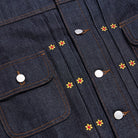 Close-up of a denim jacket with floral embroidery and buttons.