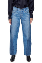 Person wearing blue jeans and black shoes on a white background