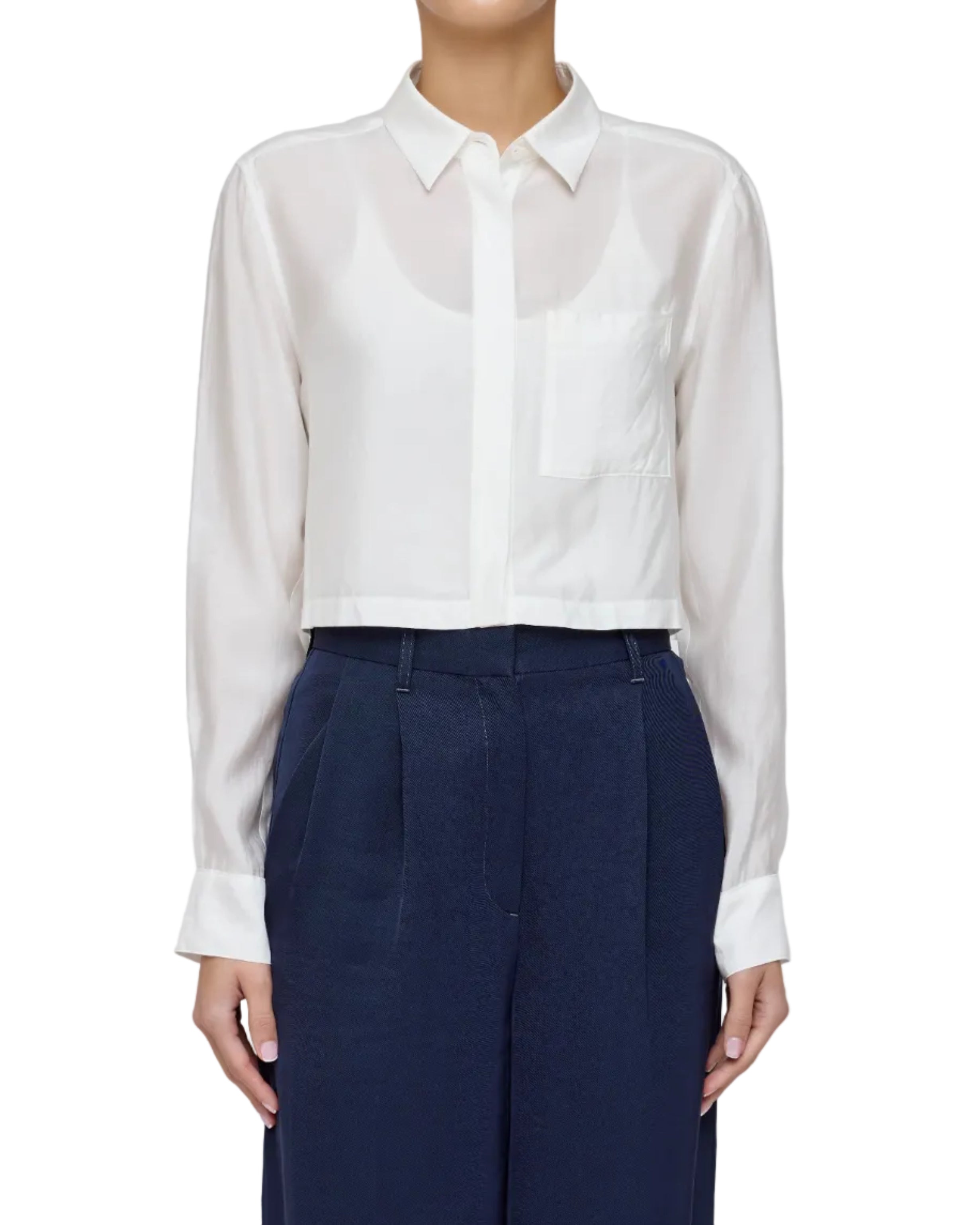 Model in a cropped white blouse on a white background