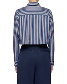 Person wearing a blue and white striped shirt with navy pants on a light gray background