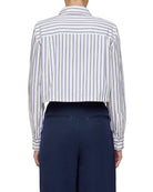 Person wearing a striped shirt and navy pants on a light gray background