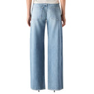 Person wearing a white top and light blue jeans on a white background