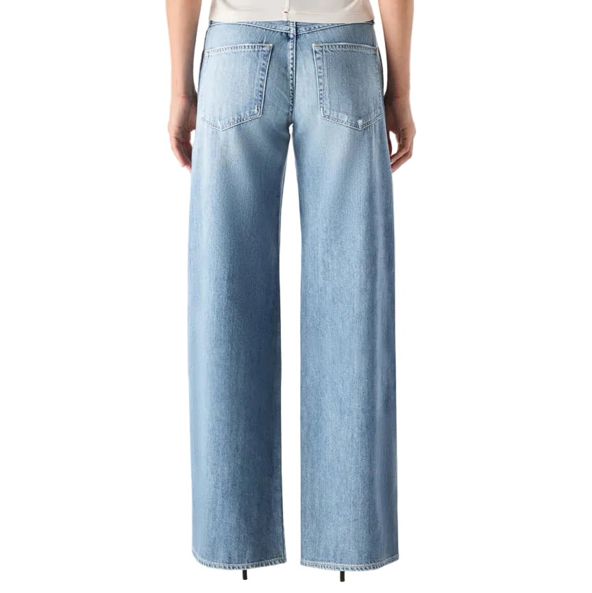 Person wearing a white top and light blue jeans on a white background