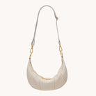 Cream leather cross body bag with gold accents on a white background