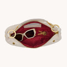 Interior view of a cream leather handbag with gold accents on a white background