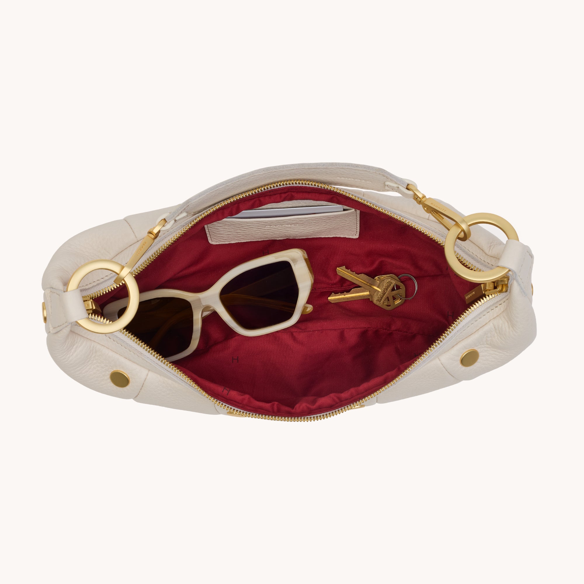 Interior view of a cream leather handbag with gold accents on a white background