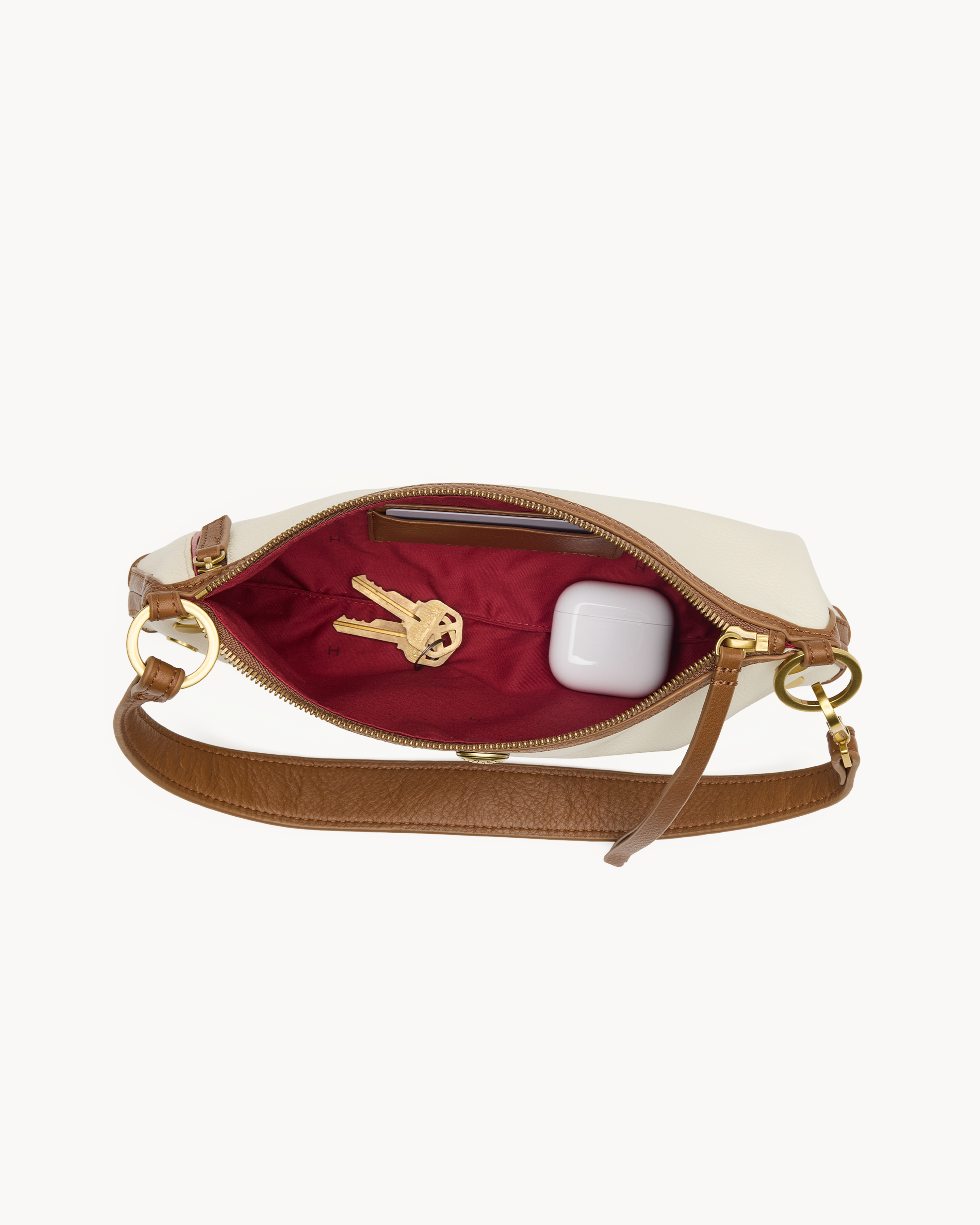 Interior view of a cream convertible handbag with brown & gold accents on a white background 