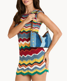 Model in a striped multicolor mini dress with a blue striped convertible bag with brown and gold accents