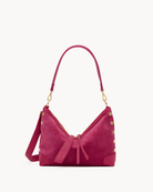 Pink suede handbag with gold accents on a white background