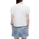 Model in a white t-shirt and denim skirt on a white background