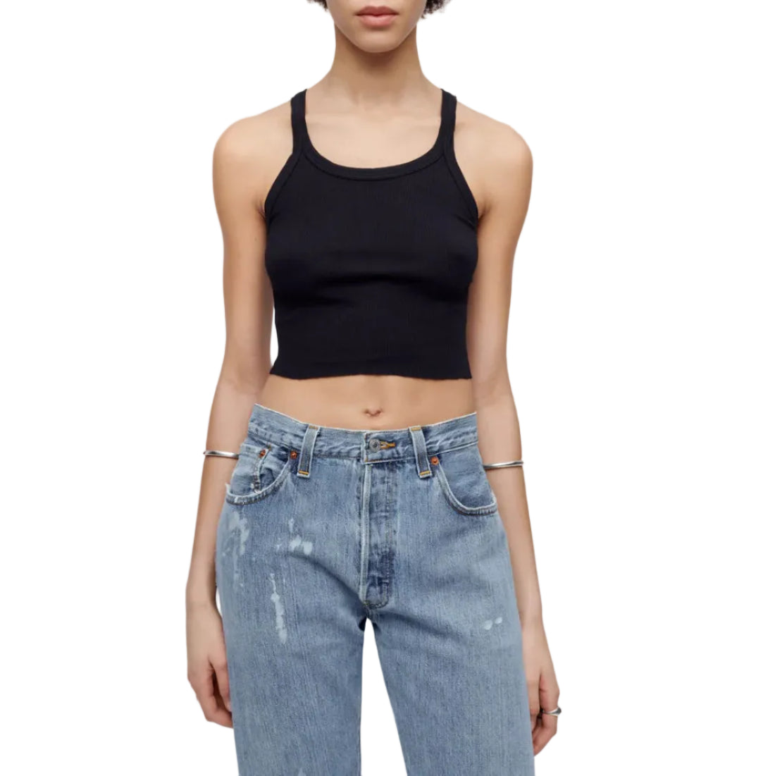Model in a black tank top and jeans on a white background