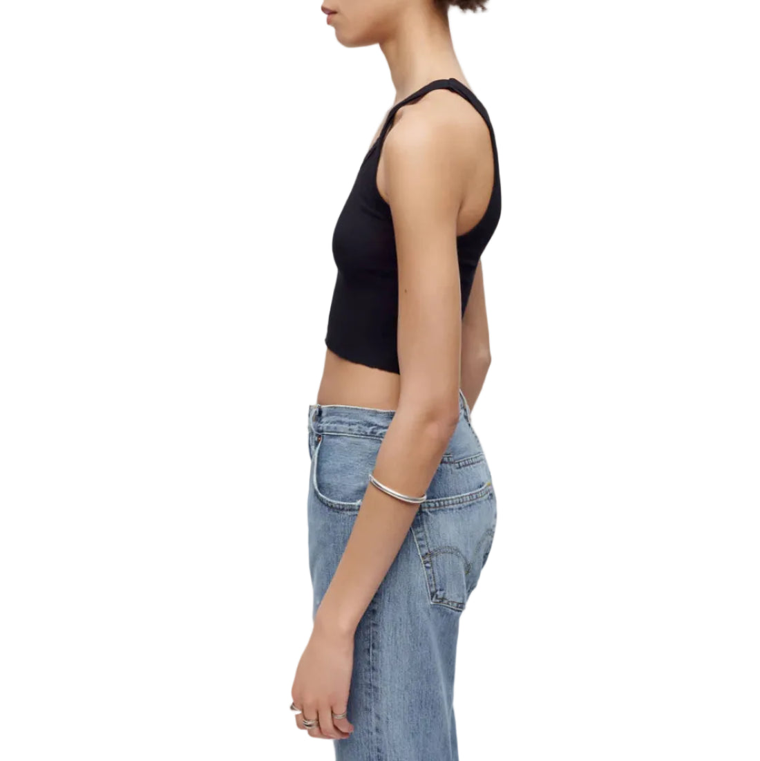 Model in a black tank top and jeans on a white background