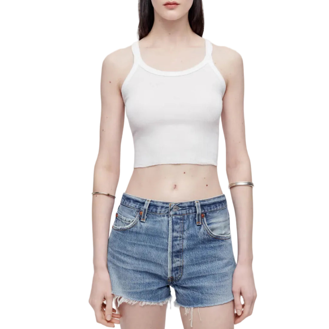 Model in a white tank top and denim shorts on a white background
