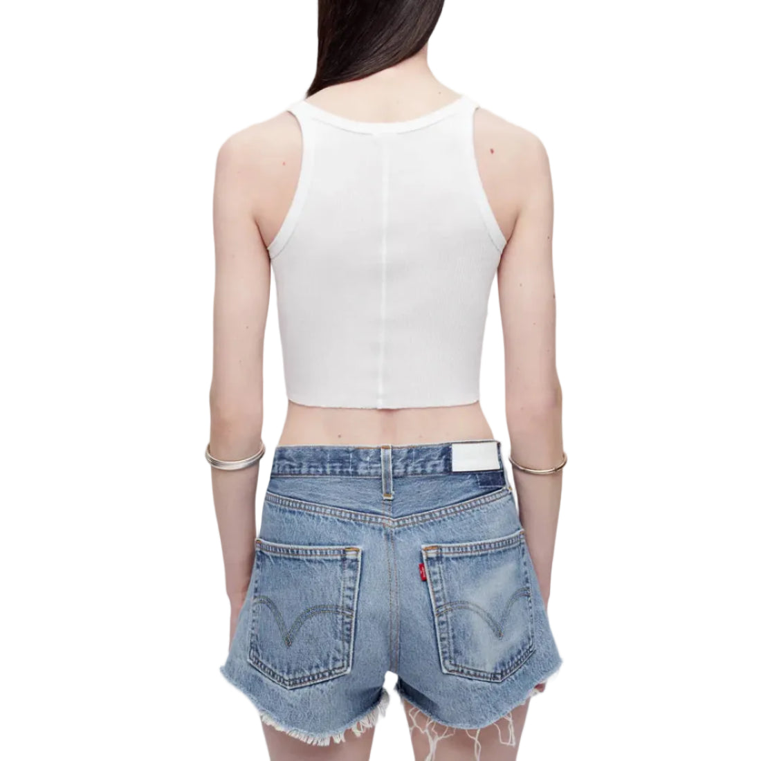 Back view of a model in a white tank top and denim shorts on a white background