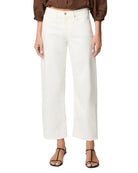 Person wearing a brown top and white pants on a plain background