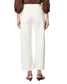 Back view of a person wearing a brown top and white pants on a plain background
